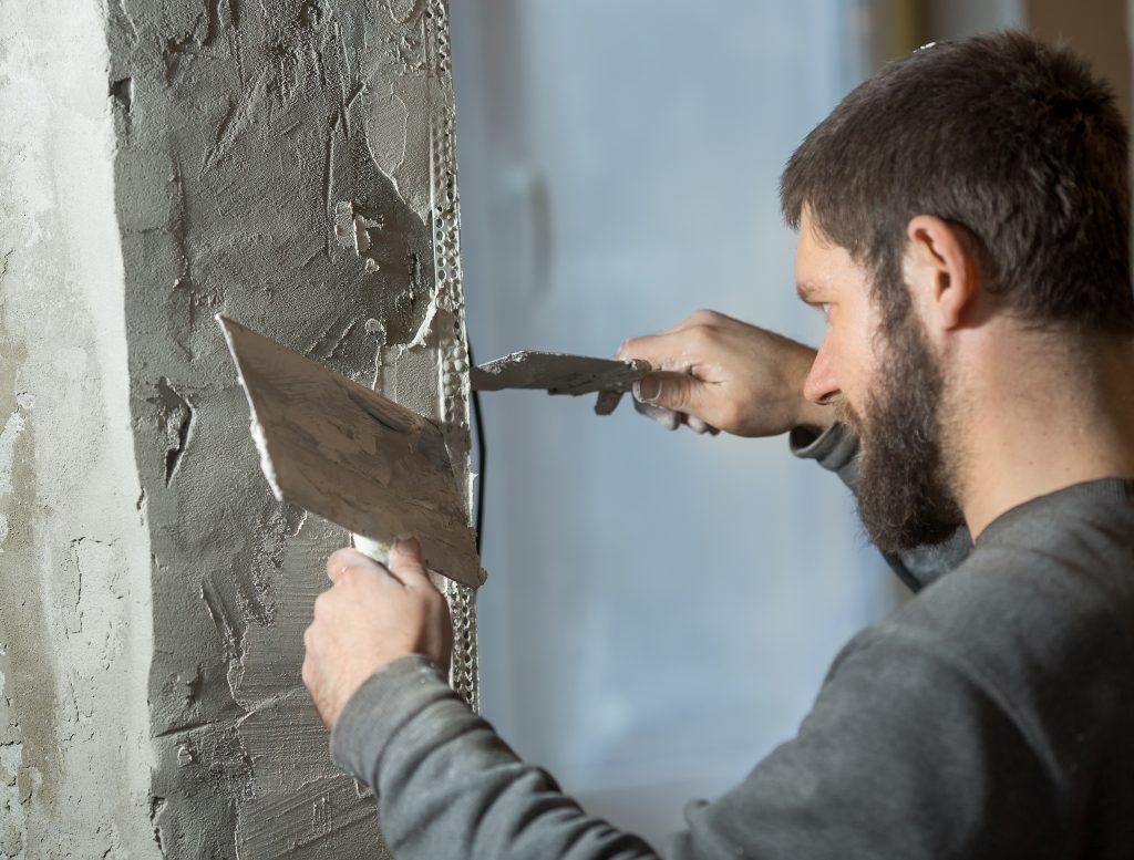 a man with a plasterer beard mounts a perforated painting corner - plastering services in Stoke on Trent